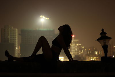 Man sitting in city at night