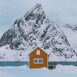 House on snow covered mountain against sky