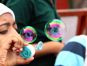 Cropped image of child blowing bubble wand