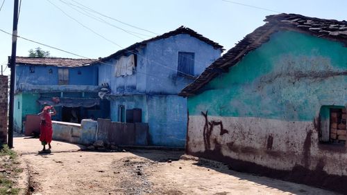 Rear view of man outside house against sky