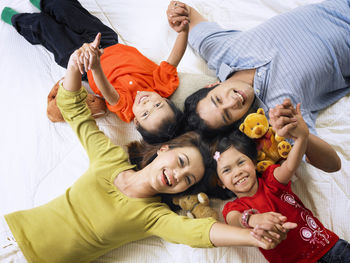 High angle portrait of happy family lying on mattress at home