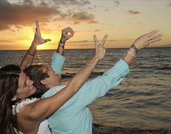 People at beach against sky during sunset