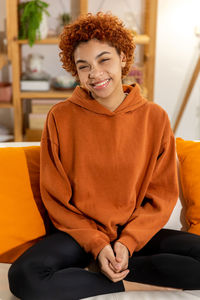 Portrait of young woman sitting on sofa at home