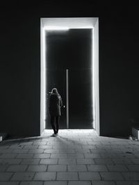 Rear view of woman standing by door at night