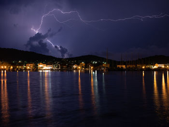Lightning over illuminated city against sky at night