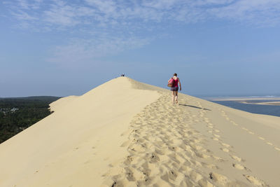 Rear view of woman walking on sand dune at desert