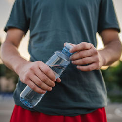 Midsection of man holding condom while standing outdoors