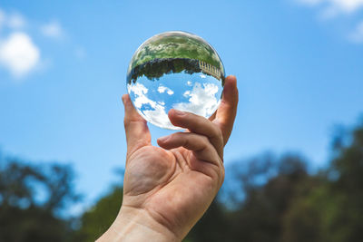 Midsection of person holding ice cream against sky