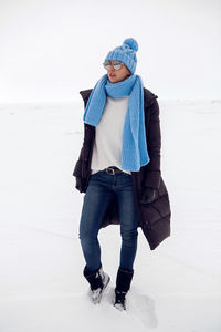 Girl running in a snowy field in a jacket and sunglasses