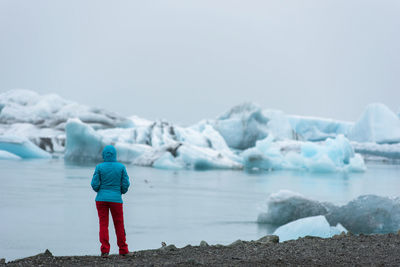 Rear view of woman standing by lake