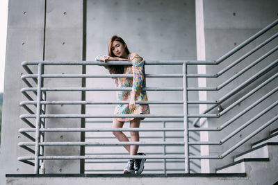 Low angle view of young woman standing against wall