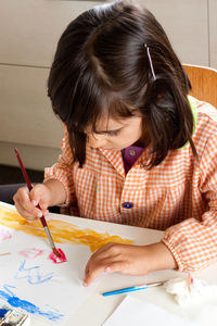 Midsection of woman holding paper while sitting on table