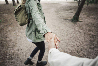 Low section of woman holding man's hand in forest