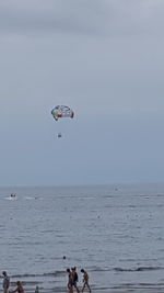 Person paragliding over sea against sky