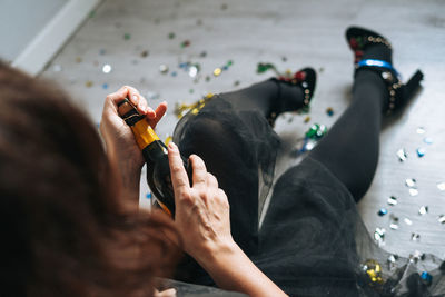 Young woman forty years plus size body positive in black dress drinks champagne at home party