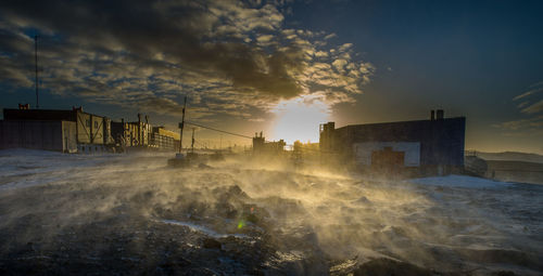 Scenic view of sea by buildings against sky during sunset