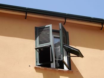 Low angle view of building with open shutters against clear sky in gibraltar. 