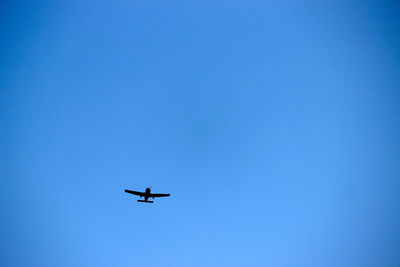 Low angle view of airplane against clear blue sky