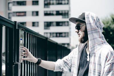 Close-up of young man entering password in security system on gate