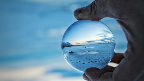 Cropped image of hand holding crystal ball with lake utah reflecting