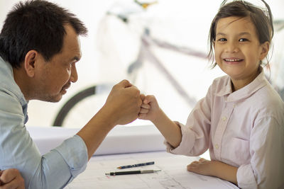 Portrait of man sitting on table with his daughter in the garage workshop.family bonding