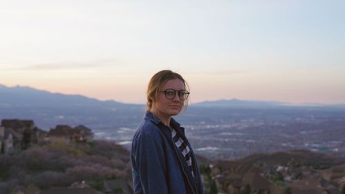 Portrait of smiling young woman standing against sky during sunset