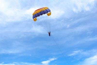 Low angle view of person paragliding against sky