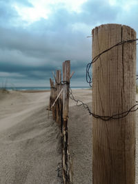 Wooden posts on beach against sky