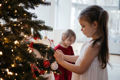 Two little girls decorating a christmas tree together