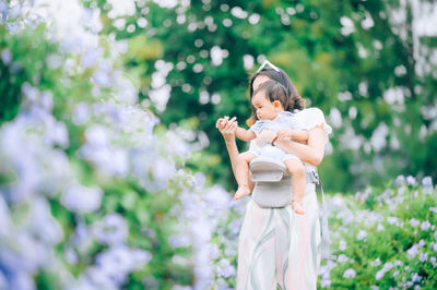 Rear view of woman standing on white flowering plants