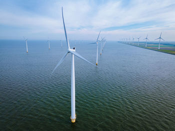 Wind turbines in sea against sky