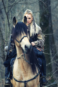 Portrait of woman riding horse in forest