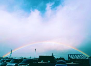 Rainbow over city against sky during sunset