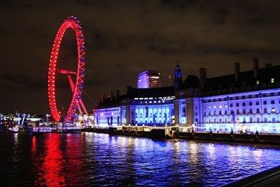 Illuminated ferris wheel in city at night