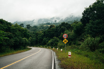 Road amidst trees and plants against sky