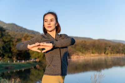 Attractive young woman stretching her arms and legs before her early morning exercise at local park