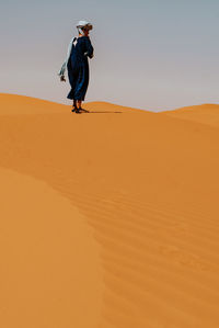 Full length man standing on sand dune in desert against sky