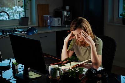 Tired woman works late at workplace in the night