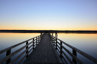 Pier over lake against clear sky during sunset