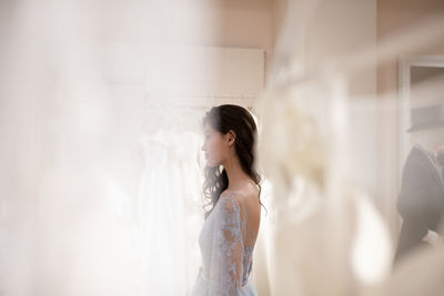 Young woman trying on dress in wedding dress shop