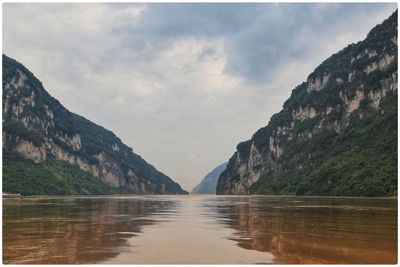 Scenic view of lake and mountains against cloudy sky