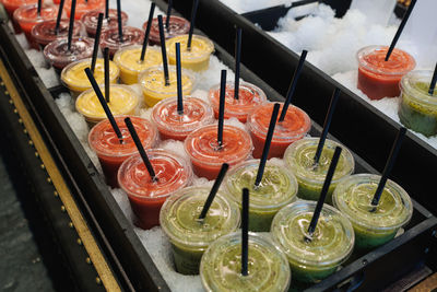 Iced fruit smoothies in the flavors of banana, grapefruit, orange, kiwi, inside glasses with straw.