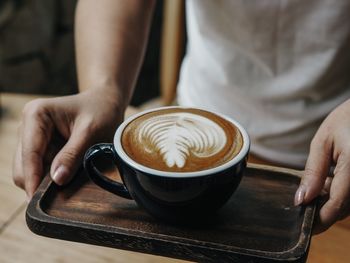 Midsection of woman holding coffee cup on table