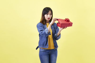 Portrait of young woman standing against gray background