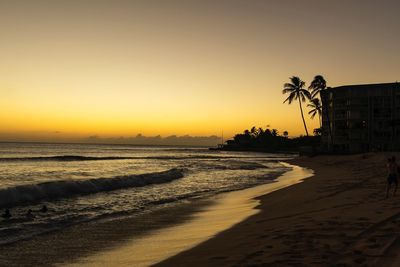 Scenic view of beach against clear sky at sunset