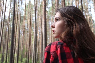 Side view of young woman looking away in forest