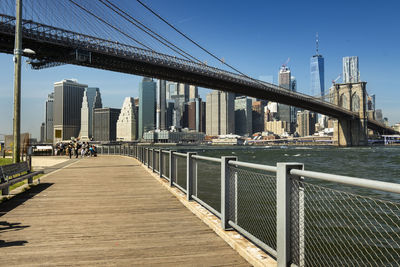 Bridge over river by buildings in city against sky