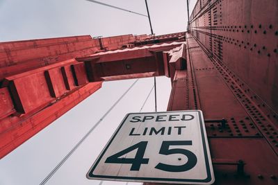 Low angle view of sign on bridge against sky