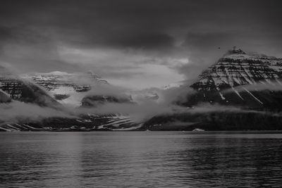 Scenic view of sea by snowcapped mountains against sky