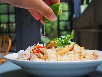 Close-up of hand squeezing lemon on food